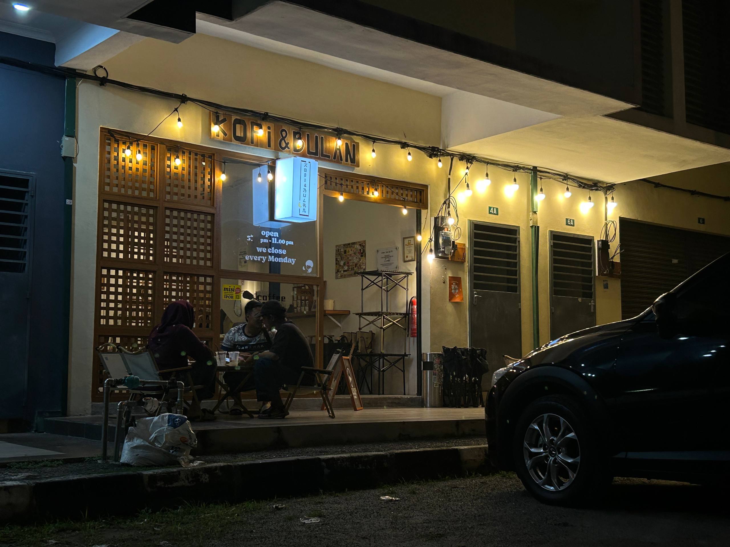 Kopi & Bulan storefront illuminated by warm lights at night